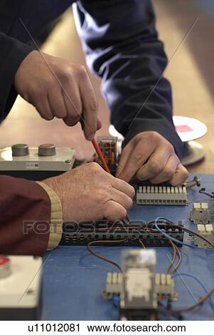 Stock Image - Electrical engineers working in shop. Fotosearch