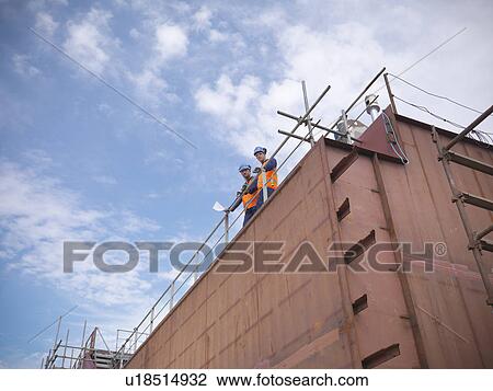 Engineers overlooking ship building View Large Photo Image Stock Image - Engineers overlooking ship building. Fotosearch