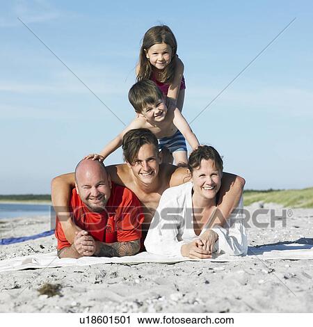 Stock Image - Family playing together on beach towel. Fotosearch