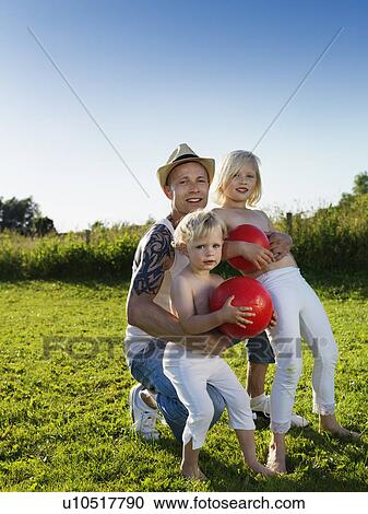 Stock Image - Father playing with daughters outdoors. Fotosearch
