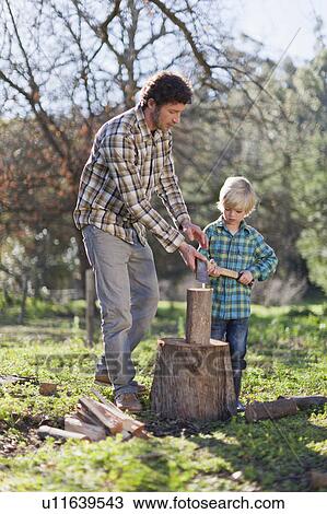 Stock Image - Father teaching son to chop wood. Fotosearch