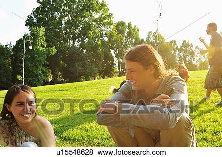 Stock Photo - Friends sitting in grass in park. Fotosearch