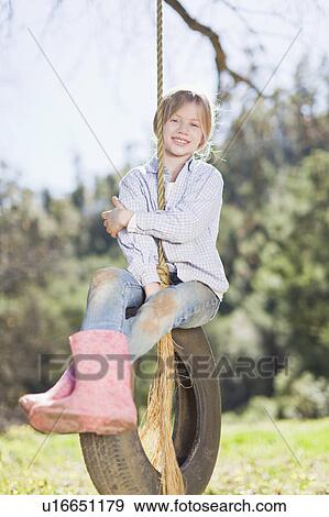 Girl sitting on tire swing outdoors View Large Photo Image Stock Photo - Girl sitting on tire swing outdoors. Fotosearch