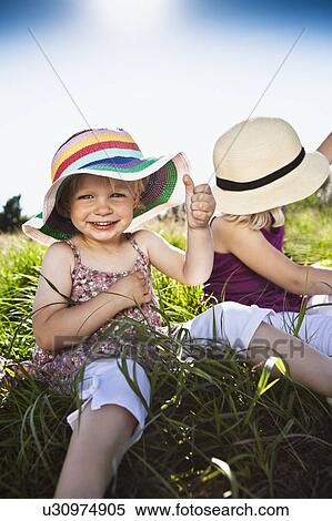 Stock Photography - Girls sitting together in grass. Fotosearch