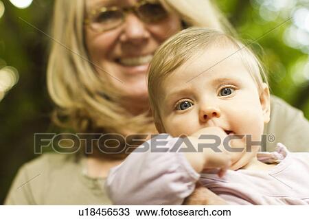 Stock Image - Grandmother holding baby outdoors. Fotosearch
