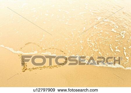 Stock Photo - Heart in sand washed away by waves. Fotosearch