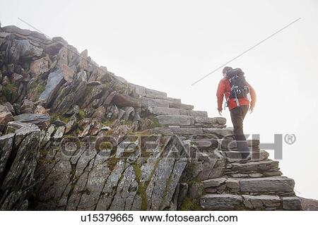 Stock Photography - Hiker climbing rocky steps on hillside. Fotosearch