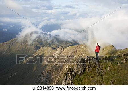 Stock Image - Hiker overlooking view from mountaintop. Fotosearch