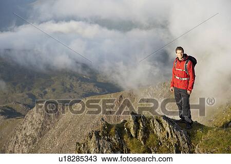 Stock Image - Hiker overlooking view from mountaintop. Fotosearch