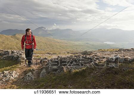 Hiker walking on rocky mountaintop View Large Photo Image Stock Image - Hiker walking on rocky mountaintop. Fotosearch