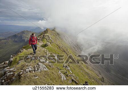 Hiker walking on rocky mountaintop View Large Photo Image Stock Image - Hiker walking on rocky mountaintop. Fotosearch