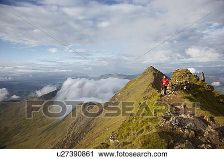 Hiker walking on rocky mountaintop View Large Photo Image Stock Image - Hiker walking on rocky mountaintop. Fotosearch