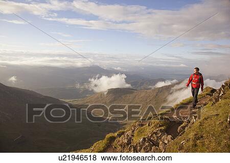 Hiker walking on rocky mountaintop View Large Photo Image Stock Photo - Hiker walking on rocky mountaintop. Fotosearch