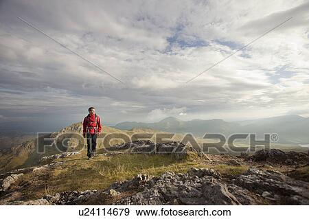Stock Photo - Hiker walking on rocky mountaintop. Fotosearch