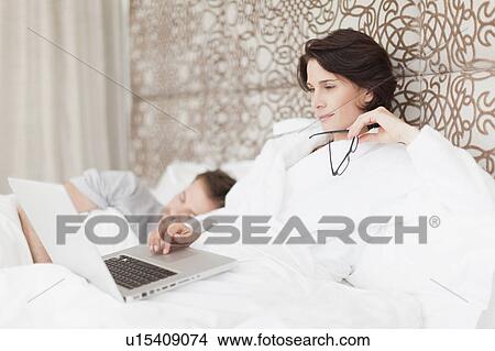 Man asleep next to working girlfriend View Large Photo Image Picture - Man asleep next to working girlfriend. Fotosearch