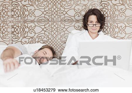 Man asleep next to working girlfriend View Large Photo Image Stock Photo - Man asleep next to working girlfriend. Fotosearch