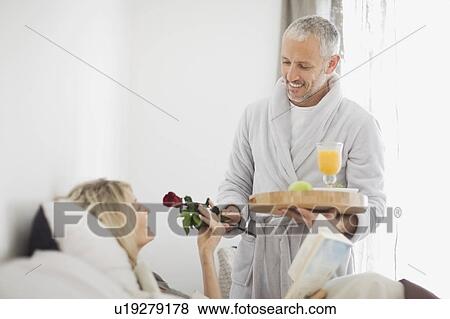 Stock Photo - Man bringing wife breakfast in bed. Fotosearch