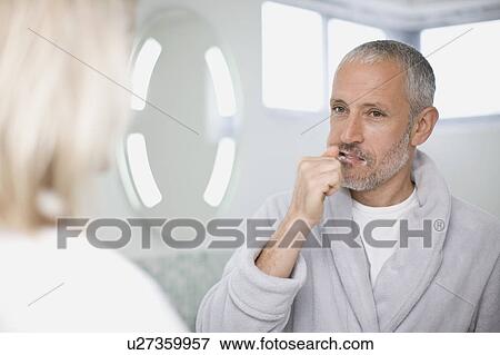 Stock Photo - Man brushing his teeth in bathroom. Fotosearch