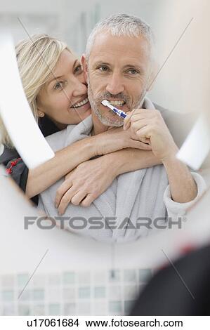 Picture - Man brushing his teeth with wife. Fotosearch