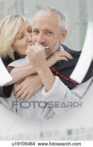 Picture - Man brushing his teeth with wife. Fotosearch