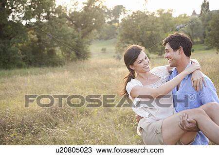 Stock Image - Man carrying girlfriend in wheatfield. Fotosearch