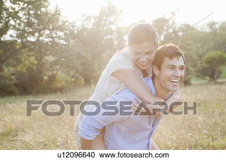 Stock Image - Man carrying girlfriend piggyback. Fotosearch
