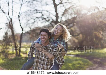 Stock Image - Man carrying girlfriend piggyback. Fotosearch