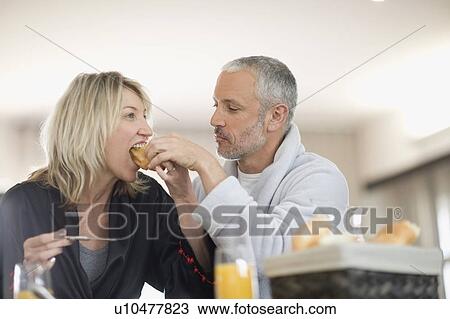 Stock Image - Man feeding breakfast to wife. Fotosearch