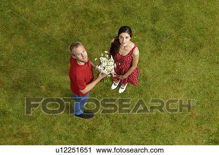 Stock Image - Man giving girlfriend flowers outdoors. Fotosearch