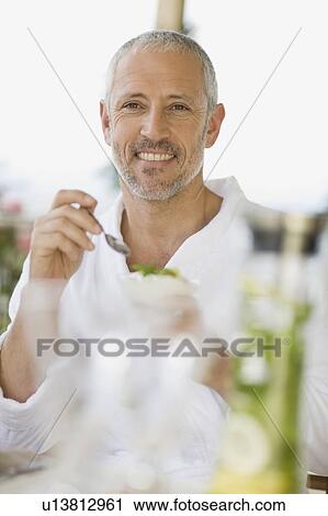 Stock Image - Man in bathrobe eating breakfast. Fotosearch