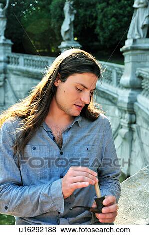 Stock Photo - Man packing pipe outdoors. Fotosearch