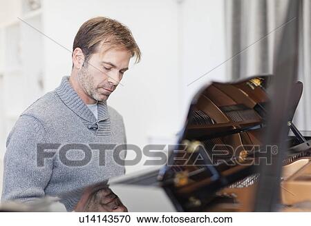 Man playing piano in living room View Large Photo Image Stock Image - Man playing piano in living room. Fotosearch