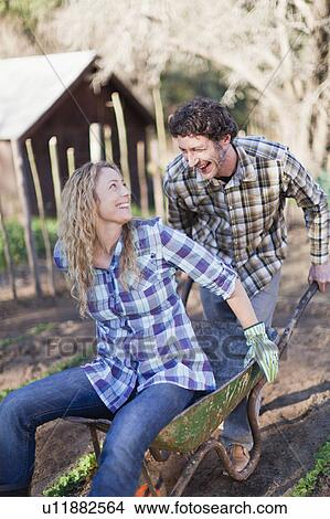 Picture - Man pushing girlfriend in wheelbarrow. Fotosearch