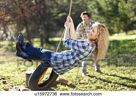 Man pushing girlfriend on tire swing View Large Photo Image Stock Photograph - Man pushing girlfriend on tire swing. Fotosearch