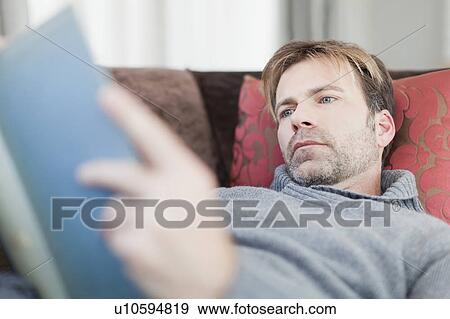 Man reading book on couch View Large Photo Image Stock Photo - Man reading book on couch. Fotosearch