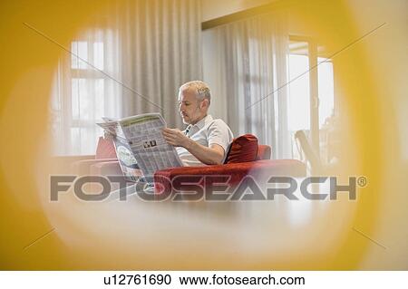 Stock Image - Man reading newspaper in armchair. Fotosearch