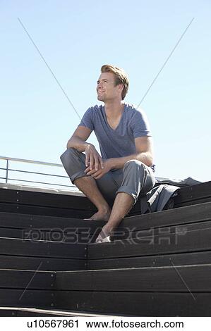 Stock Image - Man relaxing on wooden steps. Fotosearch