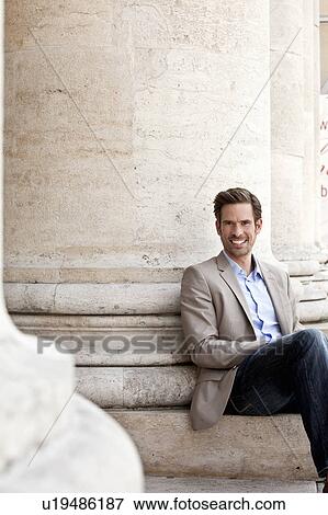 Man sitting on columned building View Large Photo Image Stock Photo - Man sitting on columned building. Fotosearch