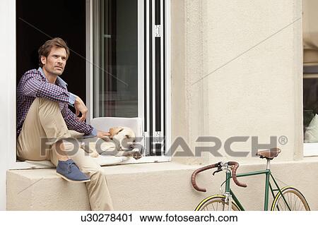 Man sitting with dog in windowsill View Large Photo Image Stock Image - Man sitting with dog in windowsill. Fotosearch