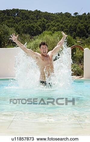 Stock Image - Man splashing in swimming pool. Fotosearch