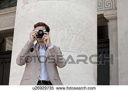 Stock Photography - Man taking pictures by columned building. Fotosearch