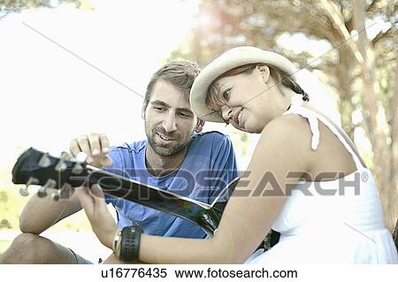 Stock Photography - Man teaching girlfriend guitar outdoors. Fotosearch