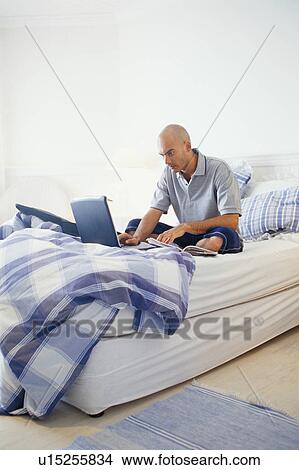 Man using laptop on bed View Large Photo Image Picture - Man using laptop on bed. Fotosearch