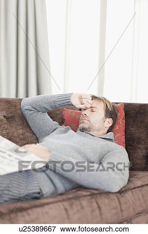 Stock Photo - Man with headache resting on couch. Fotosearch