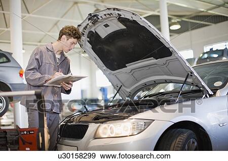 Stock Photo - Mechanic examining car engine in garage. Fotosearch