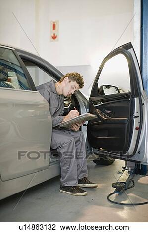 Stock Image - Mechanic examining car in garage. Fotosearch