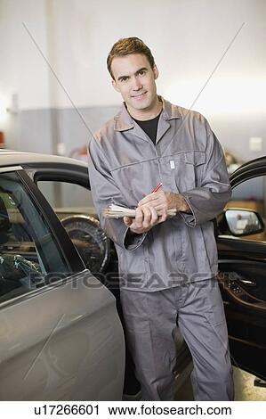 Mechanic examining car in garage View Large Photo Image Stock Image - Mechanic examining car in garage. Fotosearch