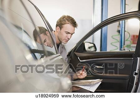 Stock Photo - Mechanic examining car in garage. Fotosearch