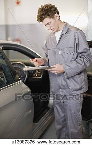 Mechanic examining car in garage View Large Photo Image Stock Photograph - Mechanic examining car in garage. Fotosearch