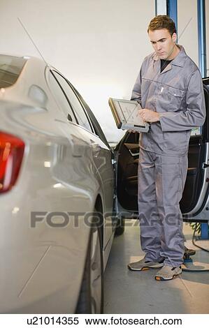 Mechanic examining car in garage View Large Photo Image Stock Photography - Mechanic examining car in garage. Fotosearch